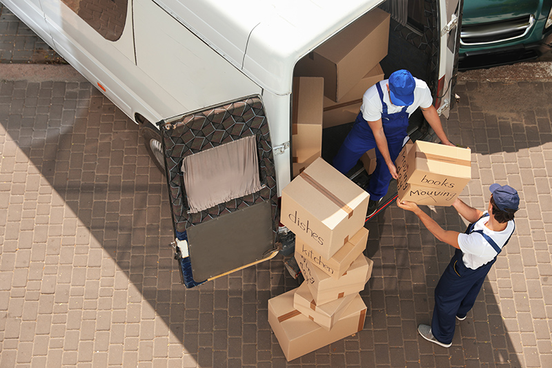 Home shifting services in Bur Dubai with professional movers carefully packing and loading household furniture, boxes, and appliances into a moving truck outside a residential building.