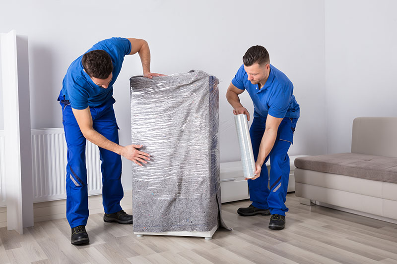 House movers in Dubai Marina providing professional home relocation service with team packing and loading furniture, boxes, and household items into a moving truck outside a residential building.