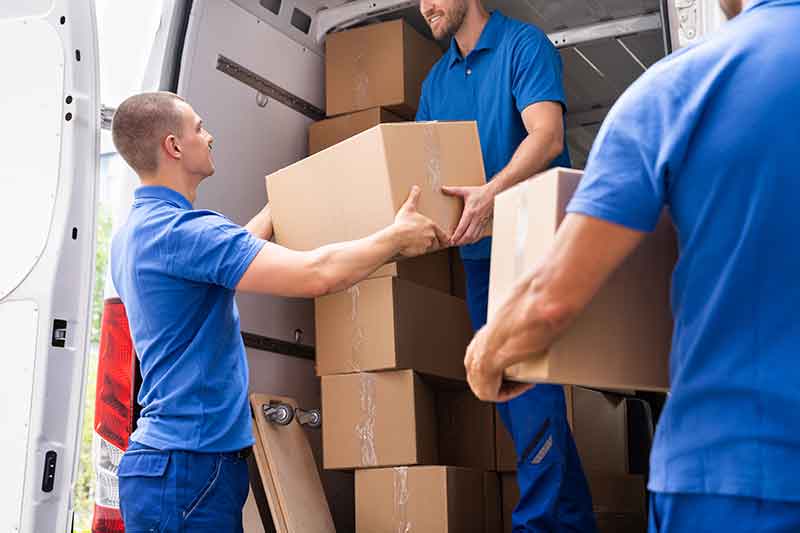 Office relocation services in Bur Dubai with professional team packing office desks, computers, files, and equipment into moving boxes and loading them into a transport truck outside a commercial building.