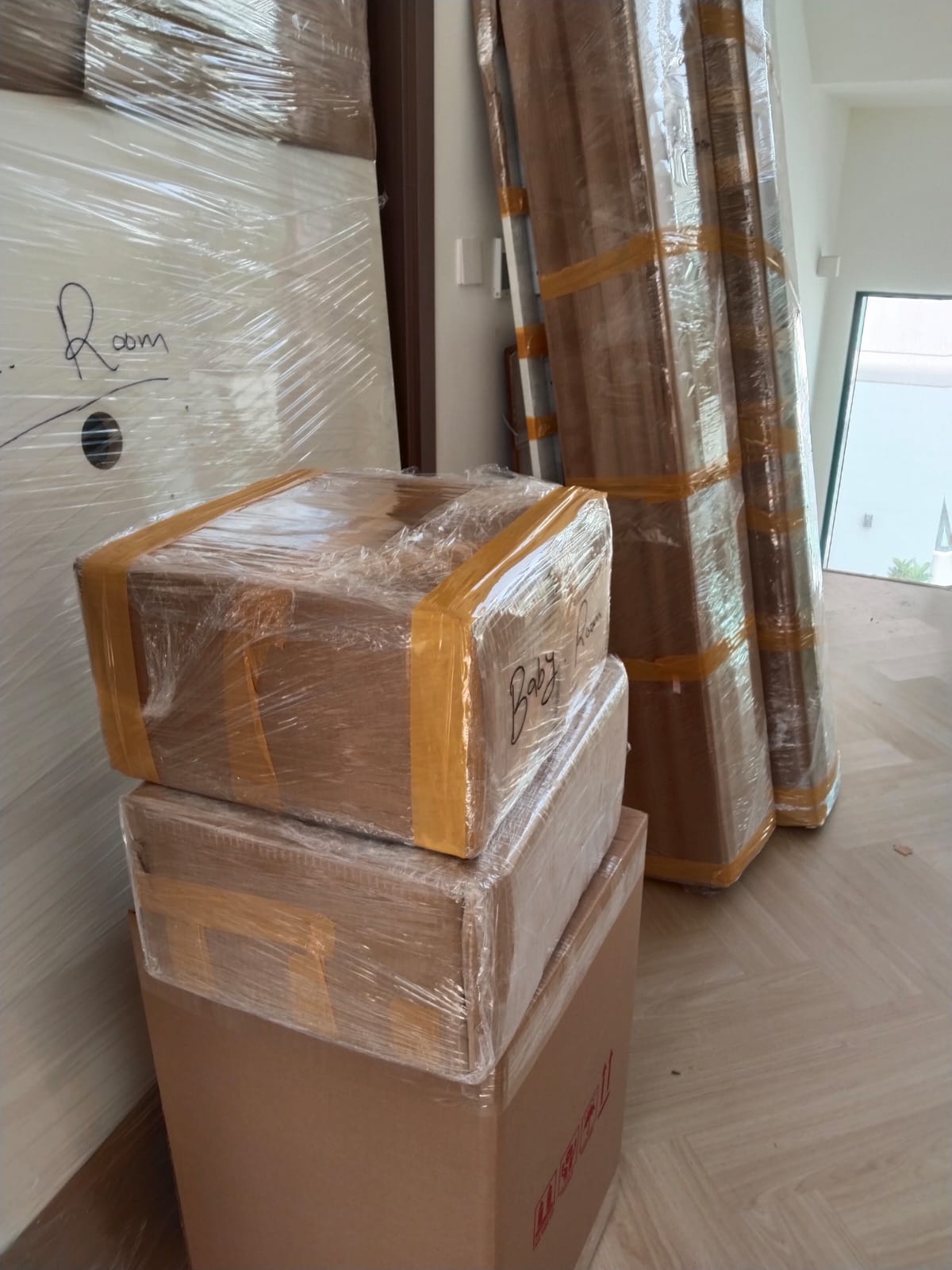 Home movers in Dubai with labeled, stretch-wrapped boxes and furniture ready for a home move