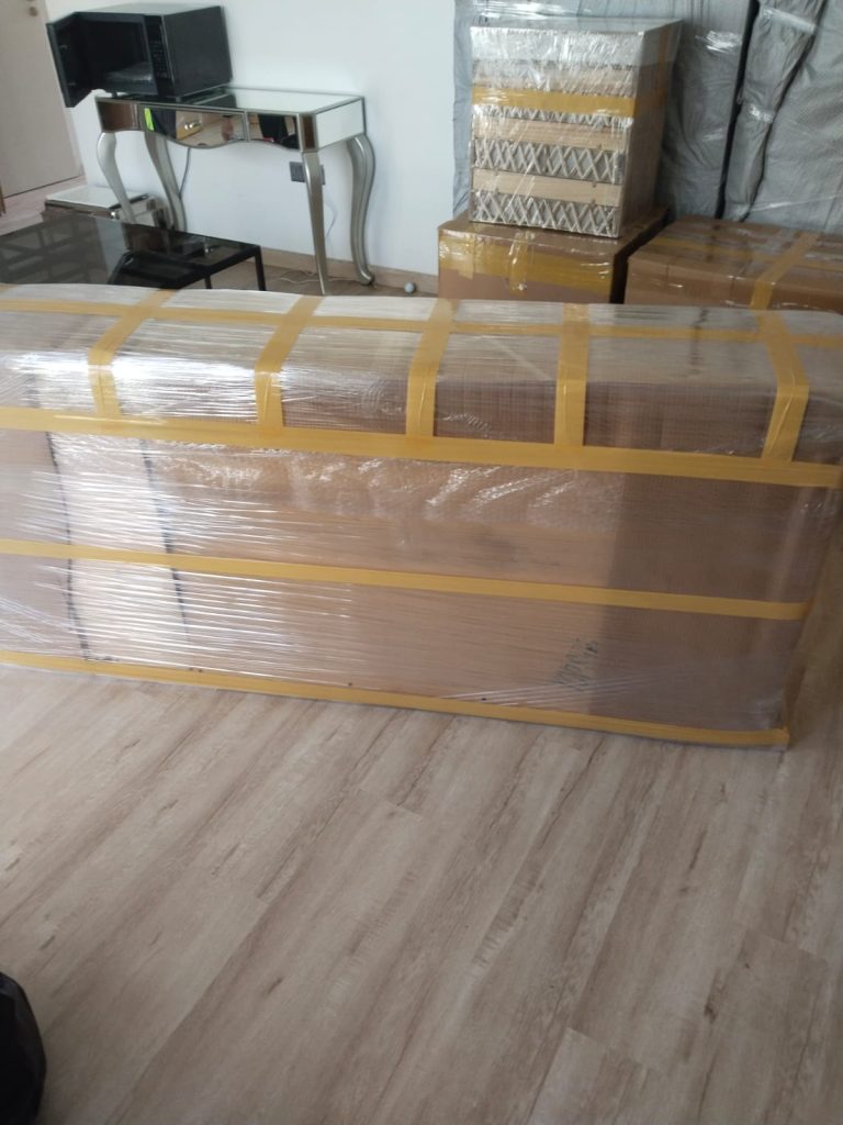 Reliable movers and packers in Dubai with a large cabinet wrapped in stretch film and strong tape