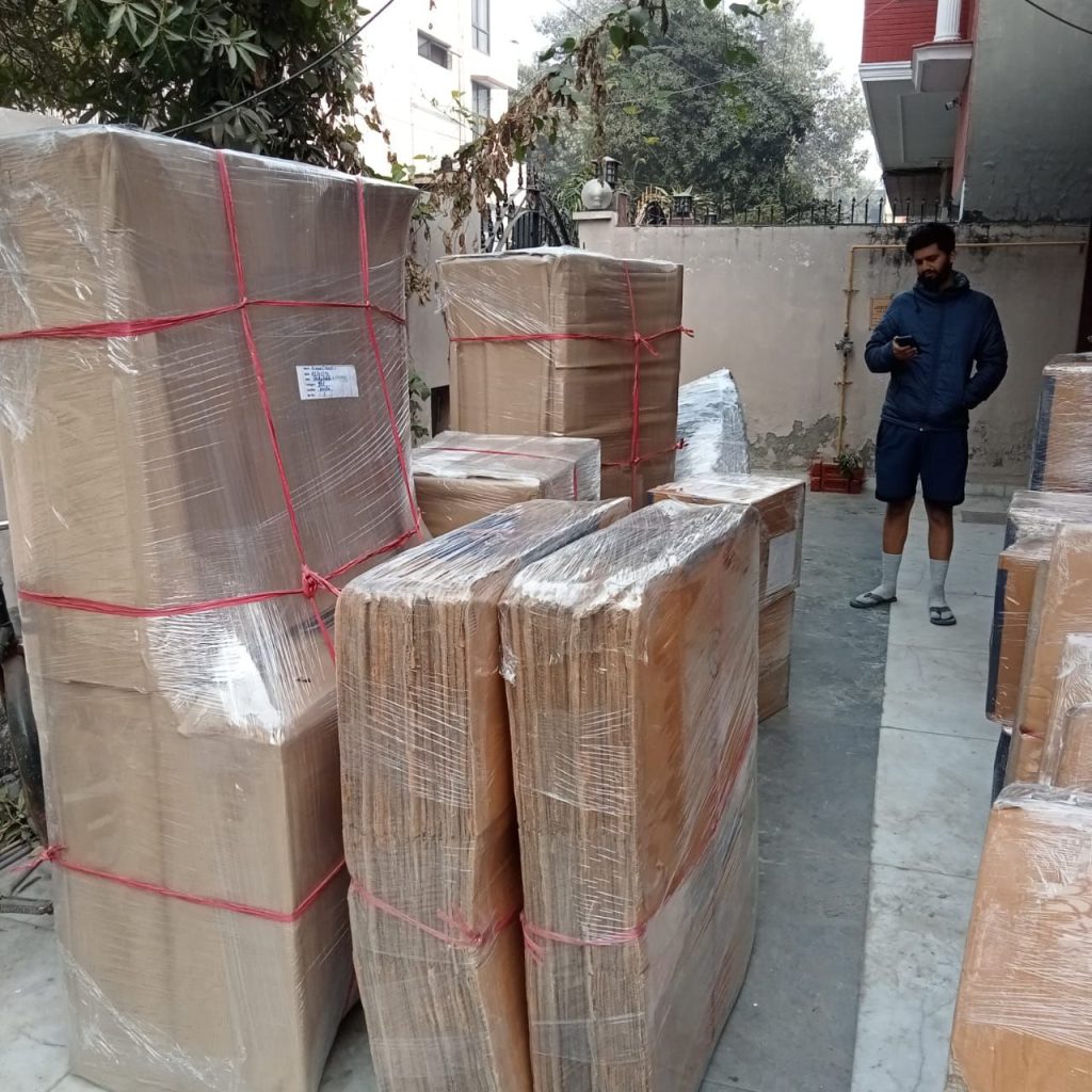 Trusted movers and packers in Dubai with boxes and furniture wrapped in stretch film and tied with straps